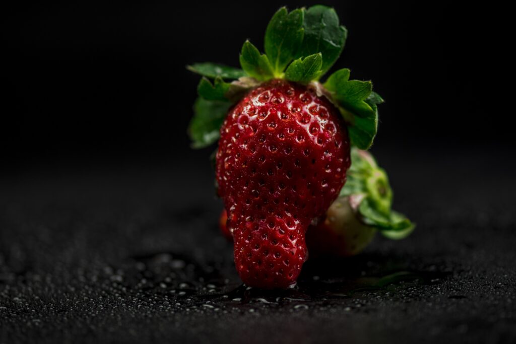 Vibrant Red Strawberry Wallpaper with Green Leaves on Dark Background