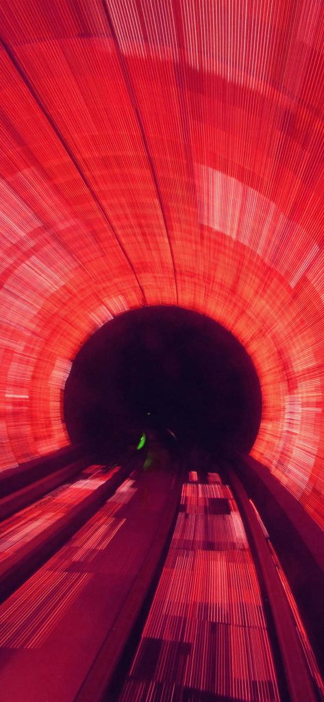 High-speed motion blur tunnel with vibrant red light streaks and dark center abstract wallpaper
