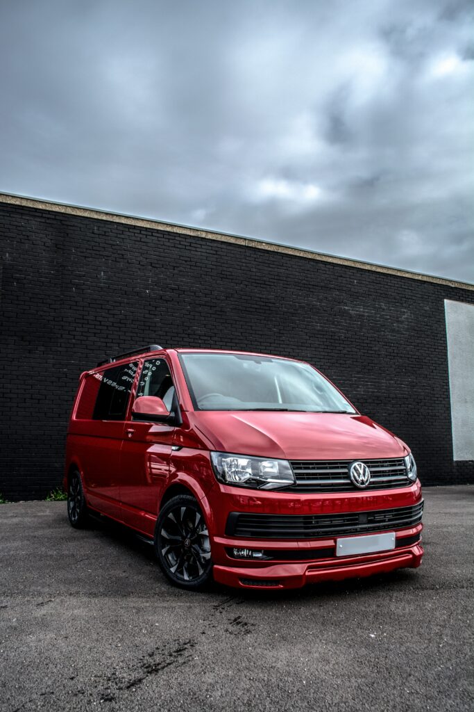 Vibrant Red Volkswagen Transporter Minivan Wallpaper on Dark Brick Wall