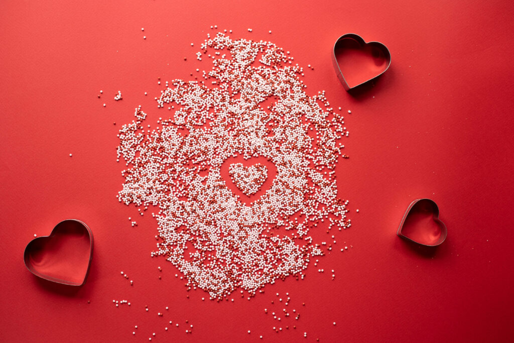 Vibrant Red Wallpaper with Heart-Shaped Chocolates & Sprinkles Design