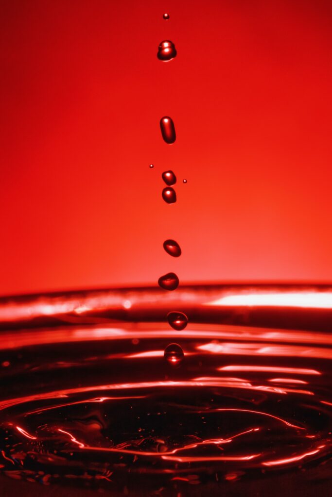 Stunning Macro: Water Droplets Splashing on Vibrant Red Wallpaper