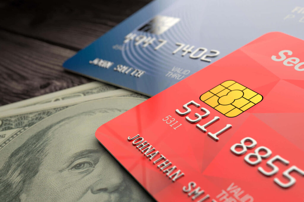 Close-up of red and blue credit cards on rustic wood table with US dollar bills underneath Wallpaper