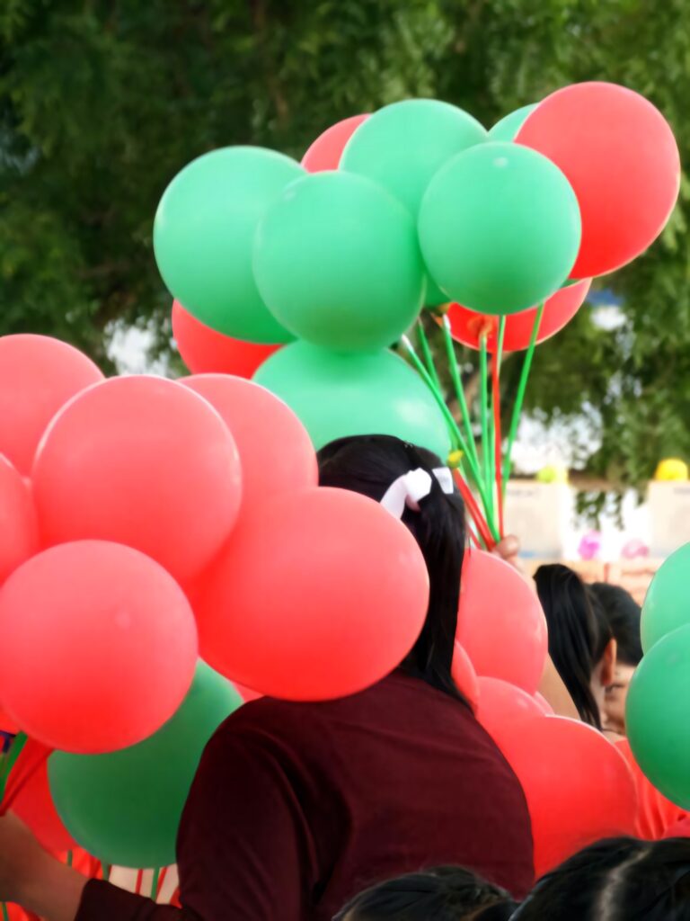 Festive Red and Green Balloons Amidst Lush Greenery Wallpaper