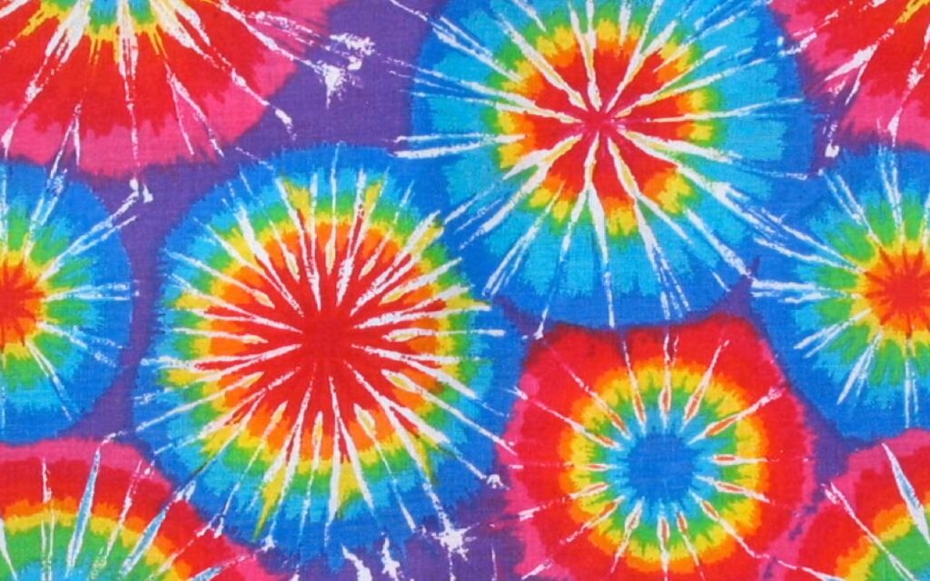 Bold tie dye wallpaper with red yellow green blue circular bursts on deep purple retro background