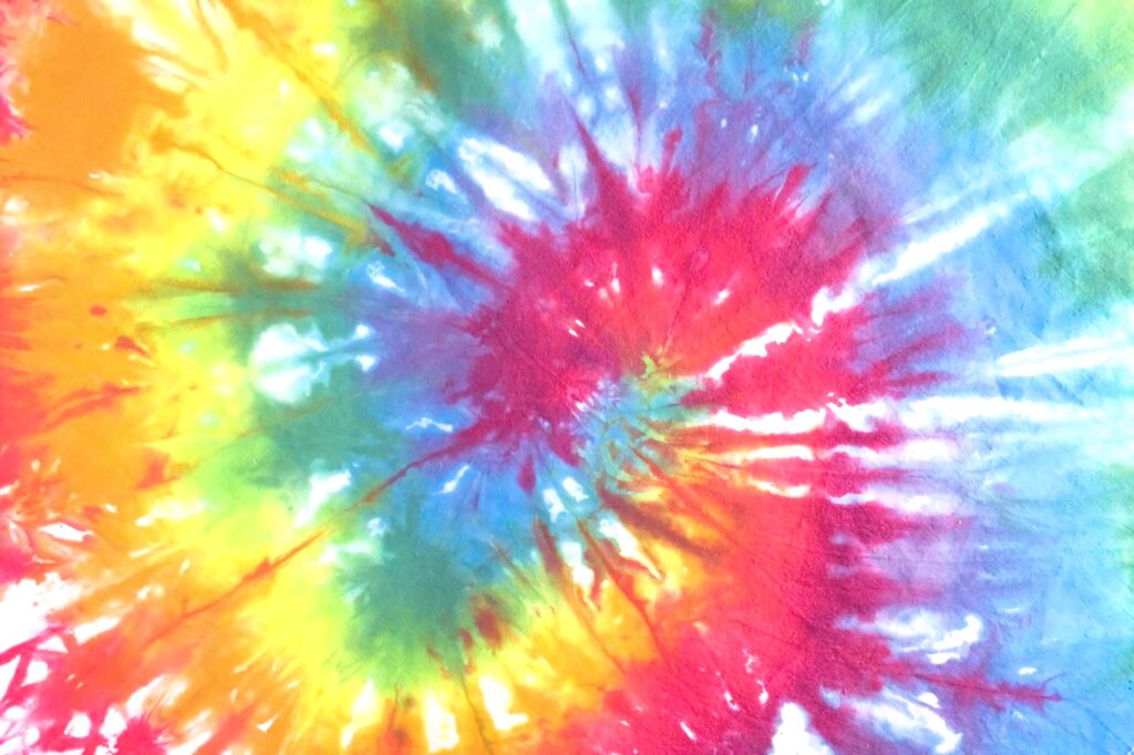 Vibrant tie-dye wallpaper with swirling yellow red blue green retro abstract pattern background