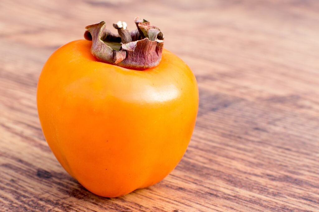 Vibrant Ripe Persimmon Fruit on Rustic Wood - Wallpaper Background