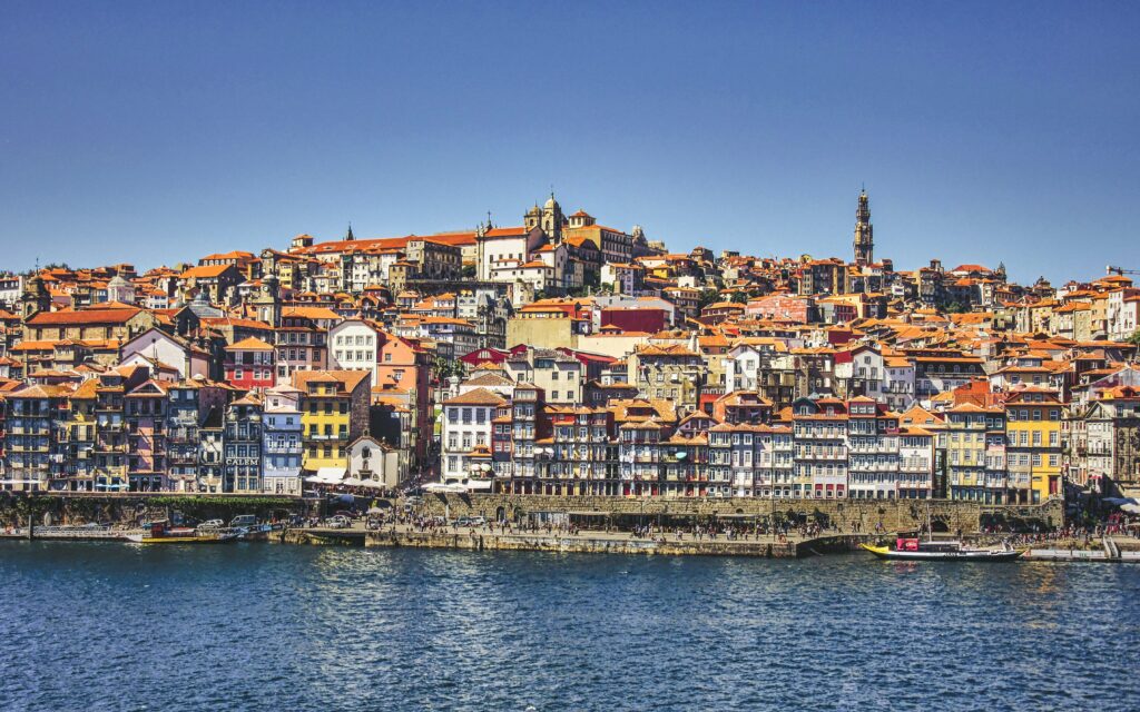 Vibrant Riverside Cityscape Wallpaper: Colorful Architecture & Blue Sky