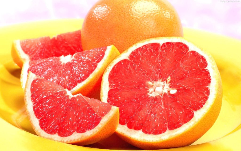 Close-up of juicy ruby red grapefruit segments on bright yellow plate vibrant citrus wallpaper