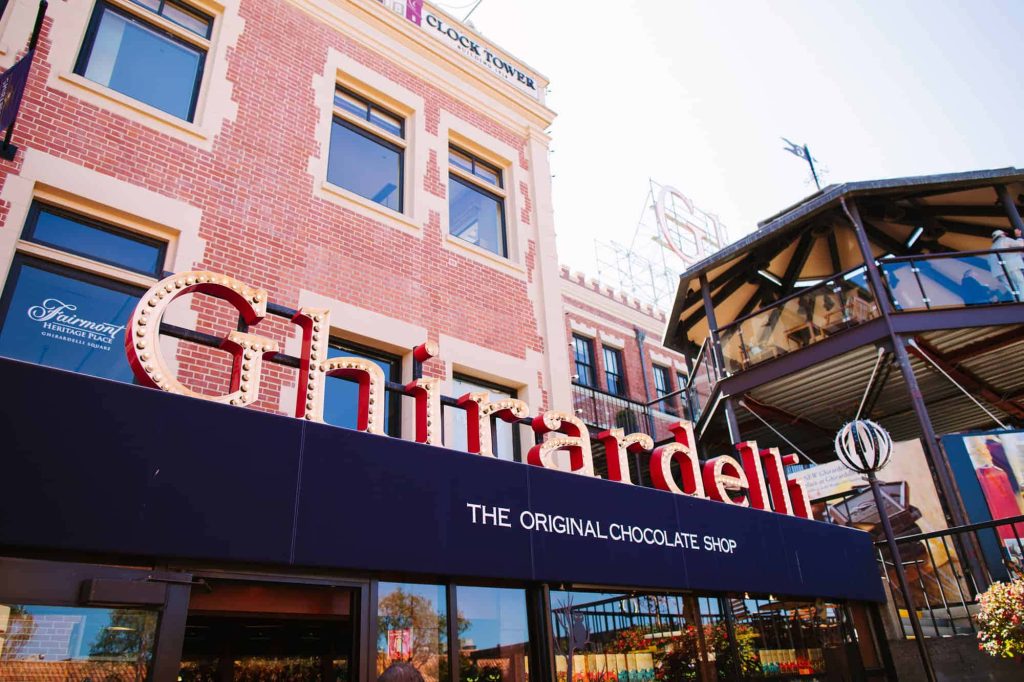 Iconic Ghirardelli Square sign and Clock Tower in San Francisco under sunny blue sky Wallpaper