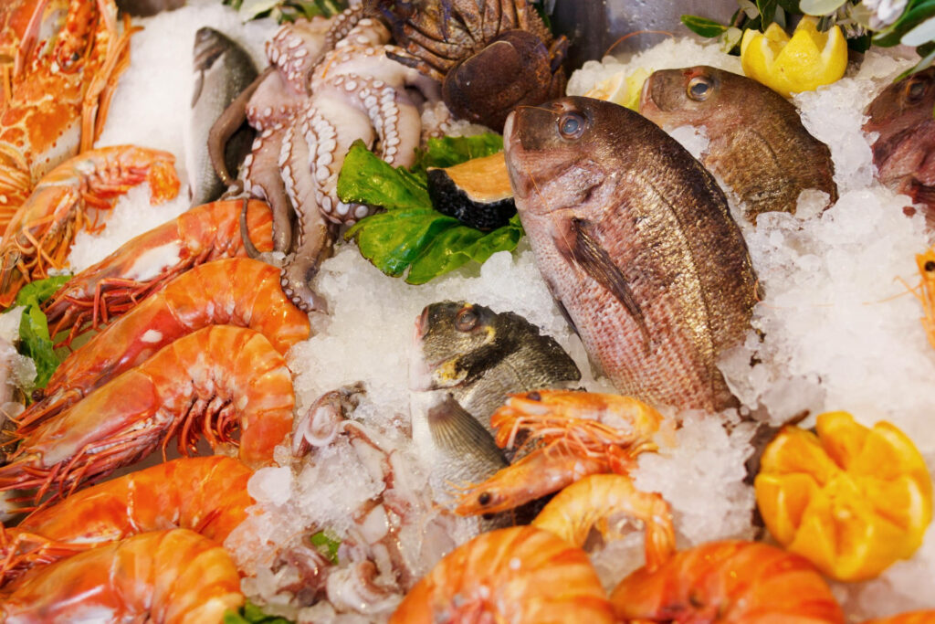 Vibrant Seafood Wallpaper: Fresh Shrimp, Fish, Octopus on Ice Background