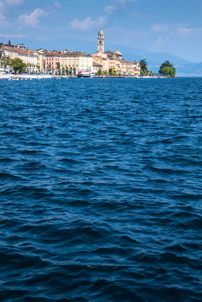 Vibrant seaside cityscape with gentle waves historic buildings and chapel tower under blue sky Wallpaper
