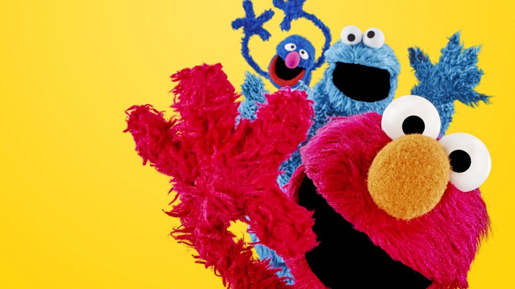 Elmo Grover and Cookie Monster playful Sesame Street wallpaper bright yellow vibrant background