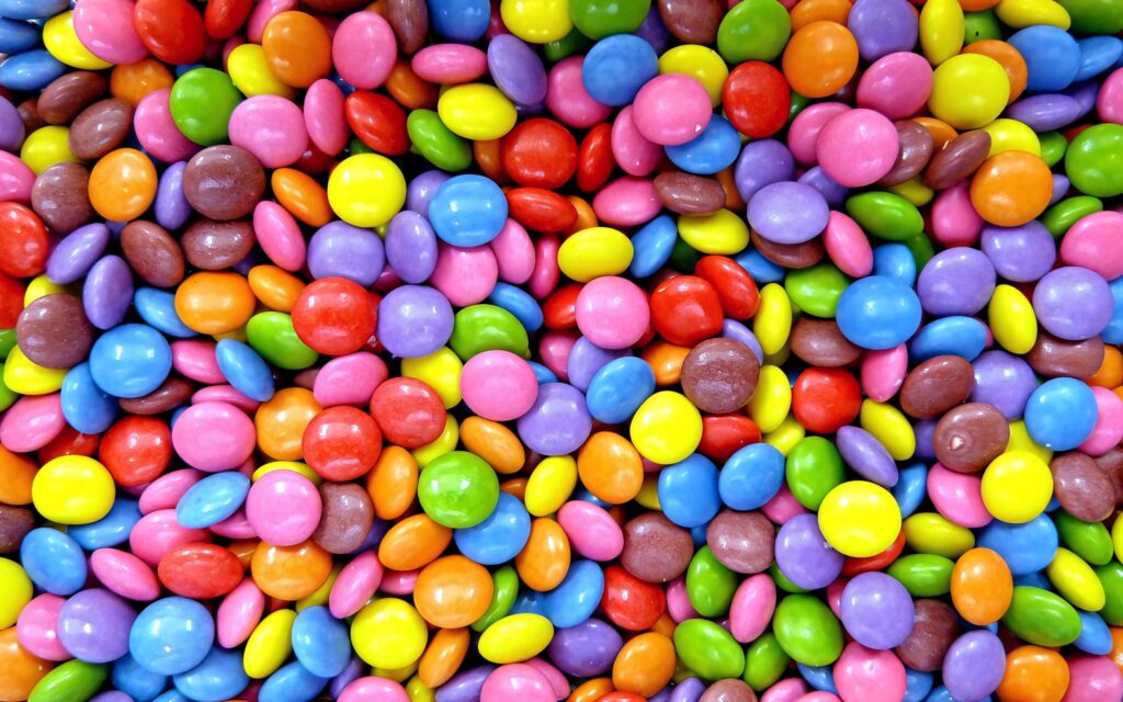 Close-up of colorful Smarties candies with bright glossy shells vibrant wallpaper background