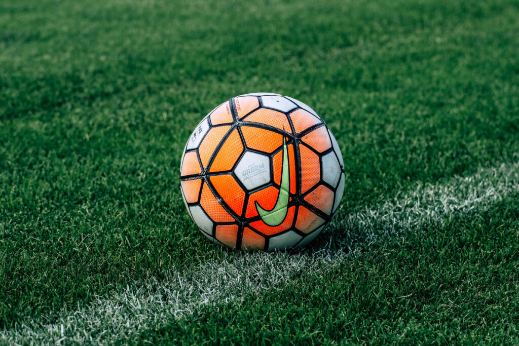 Vibrant Soccer Ball Wallpaper: Dynamic Energy on Lush Green Field