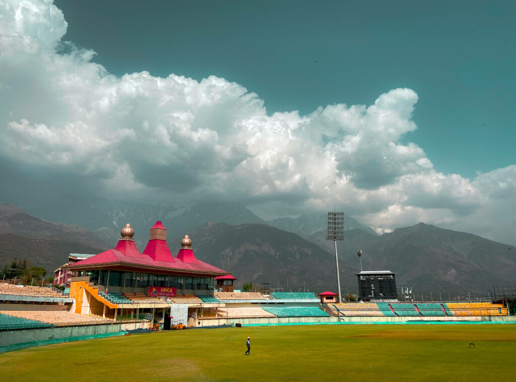 Serene Spectator Oasis: A Vibrant Cricket Arena Surrounded by Lush Greenery Wallpaper