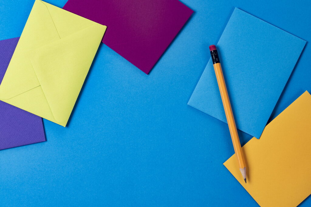 Vibrant Palette on Vintage Canvas: A Captivating Wallpaper of Assorted Colored Paper and a Rustic Brown Wooden Pencil