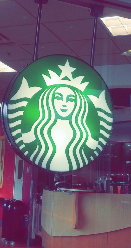 Vibrant Starbucks logo inside modern coffee shop perfect iPhone wallpaper for coffee fans