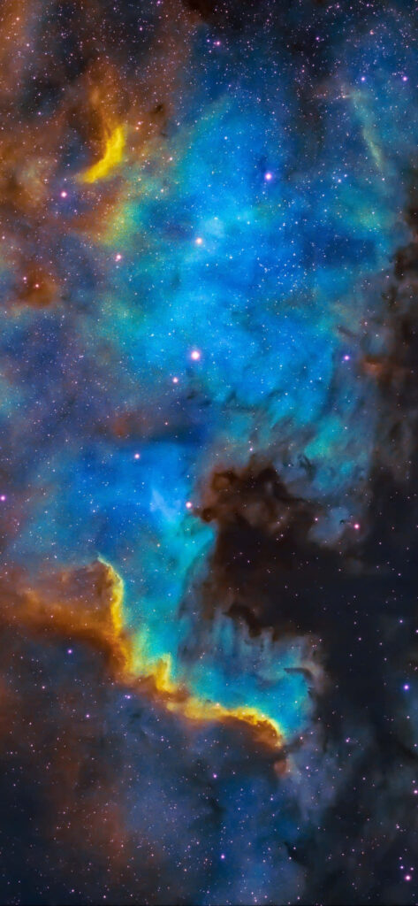 Vibrant stellar nebula wallpaper with blue and yellow hues against dark cosmic clouds.