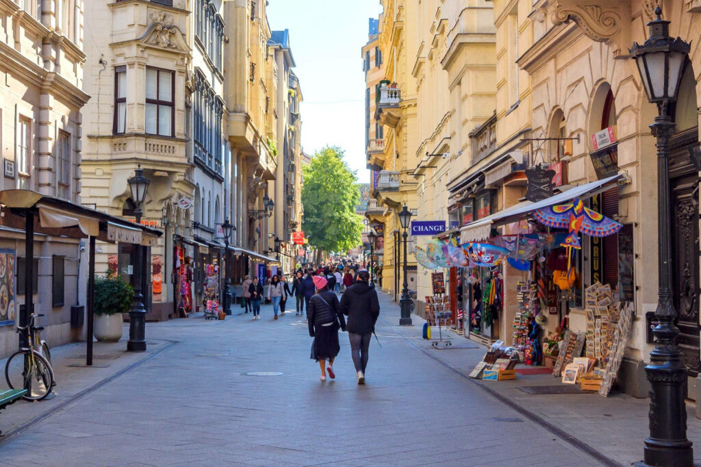 Charming City Street Wallpaper: Lively Urban Scene with Historic Shops