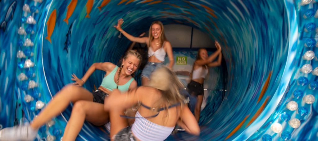 Friends laughing inside colorful spinning ocean-themed barrel ride vibrant amusement park wallpaper