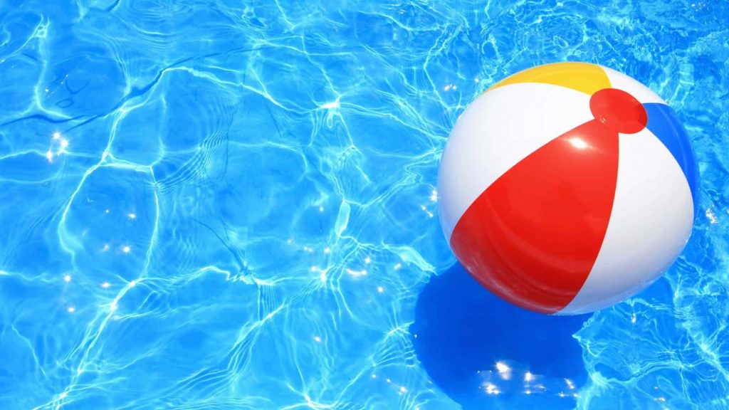 Colorful beach ball floating on clear pool water with bright sunny ripples summer vibe Wallpaper