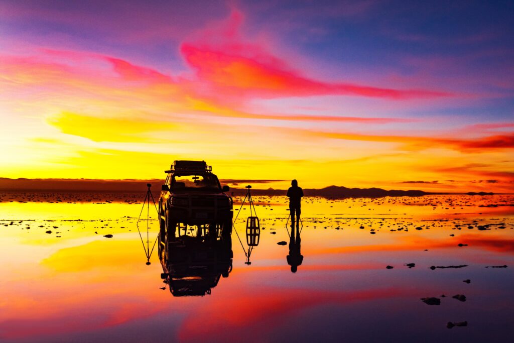 Photographer captures vibrant sunrise with yellow pink purple hues reflected in calm water landscape Wallpaper