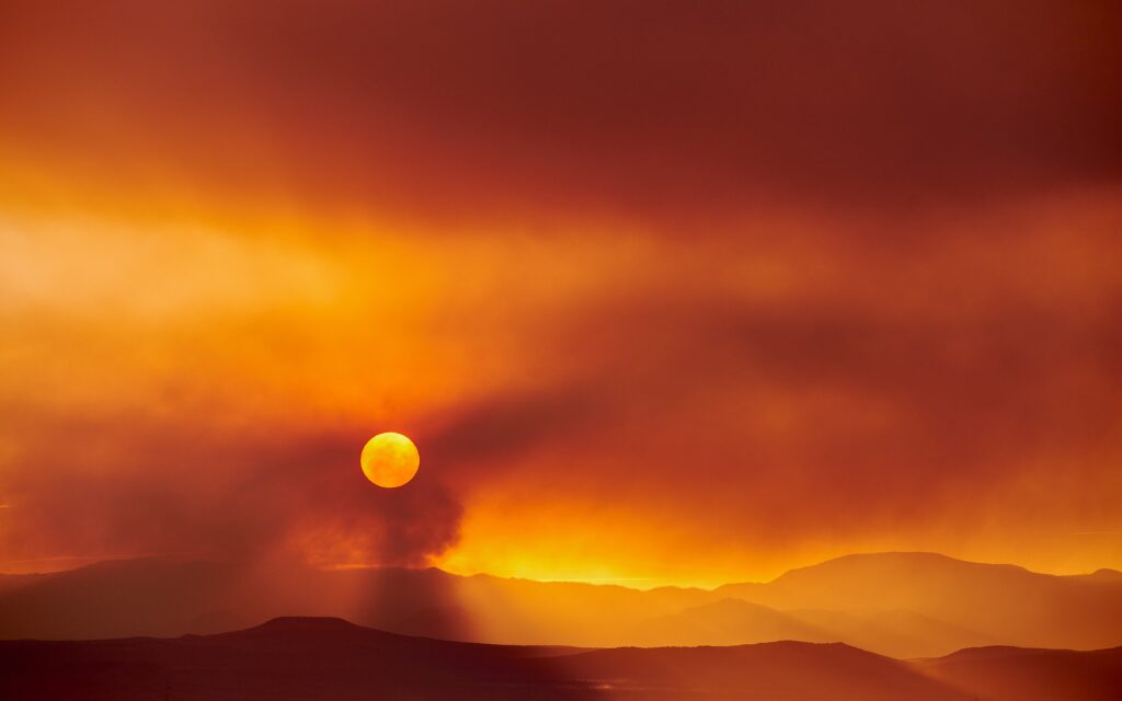 Vibrant sunset behind rugged mountains with orange and gold clouds warm landscape wallpaper