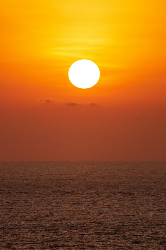 Vibrant sunset over calm sea with warm orange and gold hues serene peaceful wallpaper background