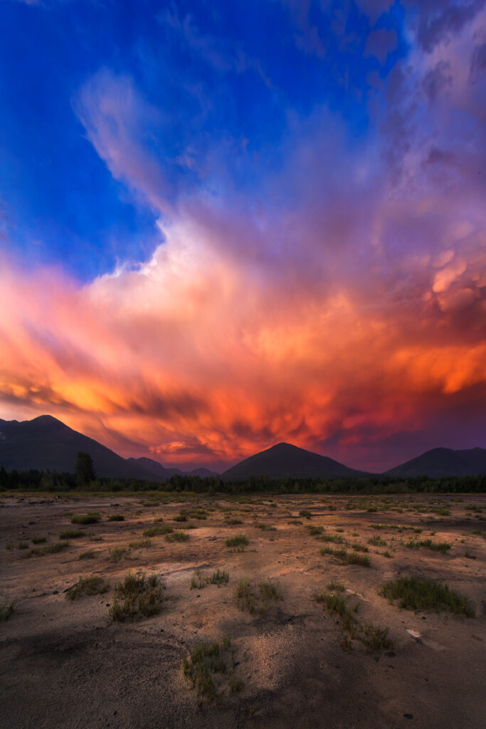 Striking sand dunes under vibrant sunset sky with warm orange red and deep blue purple clouds Wallpaper