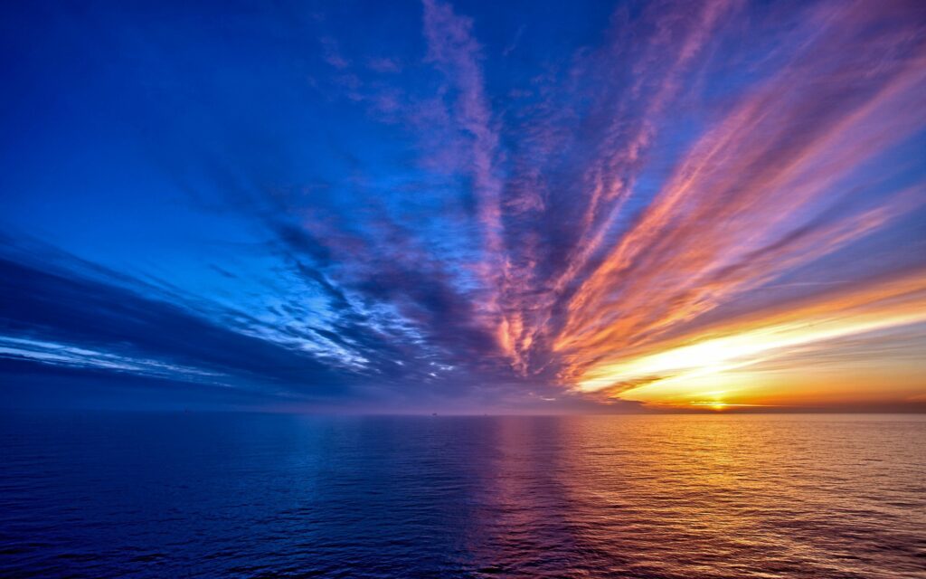 Sunset seascape wallpaper with vibrant orange blue sky and reflective rippled sea surface