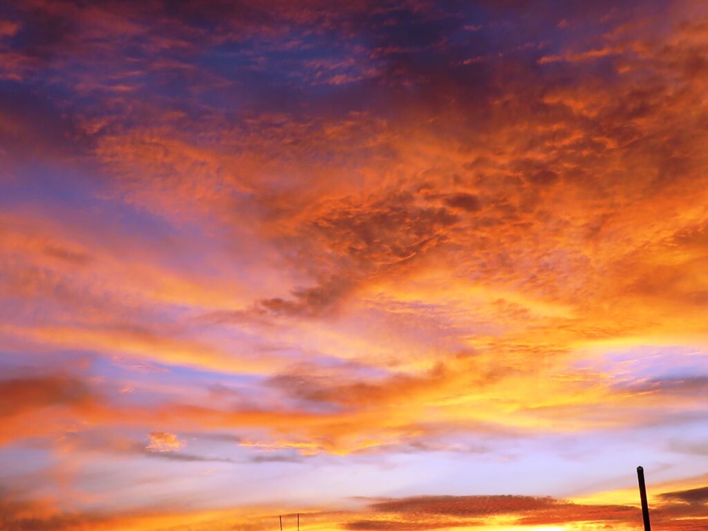 Vibrant sunset sky with dramatic orange purple and gold clouds creating stunning wallpaper background