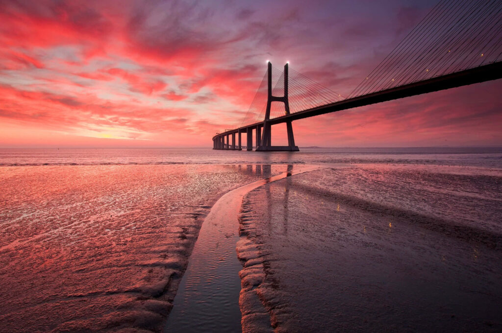 Vibrant Vasco de Gama Bridge Wallpaper at Sunset - Tranquil Water Scene