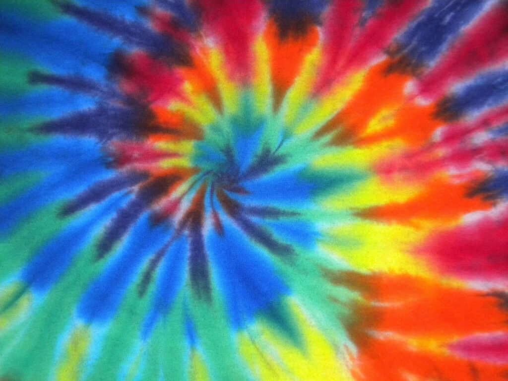 Vibrant swirling tie dye wallpaper with bold blue yellow red green and orange psychedelic pattern