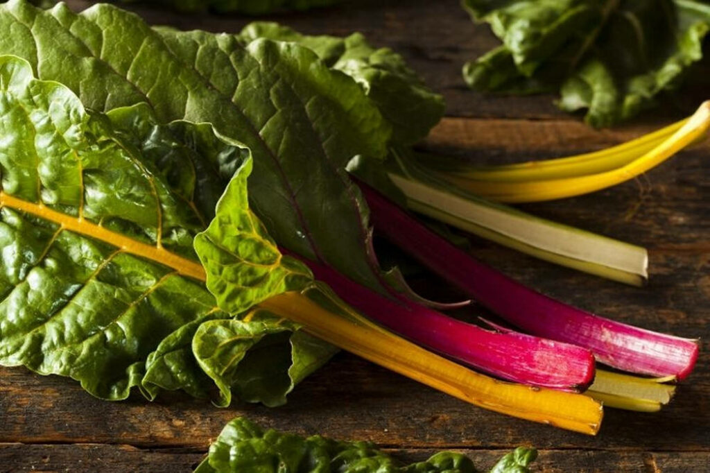 Vibrant Swiss Chard Wallpaper: Colorful Leaves on Rustic Wood Table