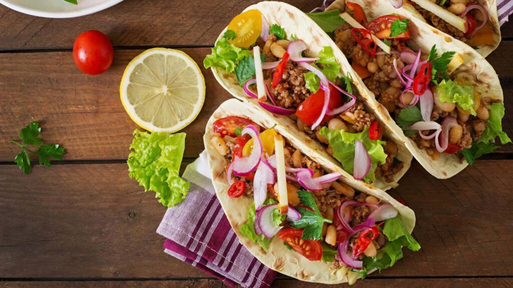 Vibrant Tacos with Fresh Veggies & Salsa on Rustic Wooden Table Wallpaper