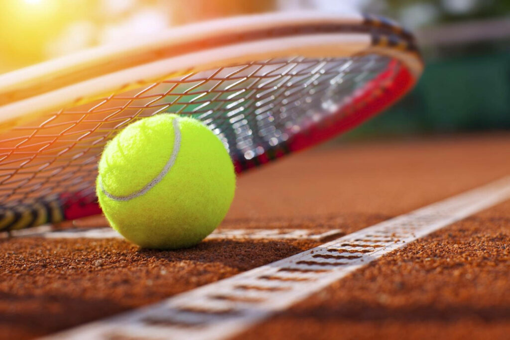 Vibrant Tennis Wallpaper: Racket & Ball on Clay Court in Sunlight