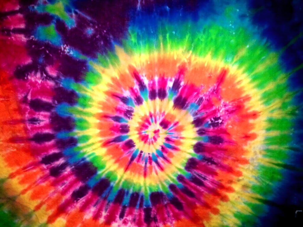 Vibrant tie-dye spiral wallpaper with yellow red green blue and purple psychedelic pattern background