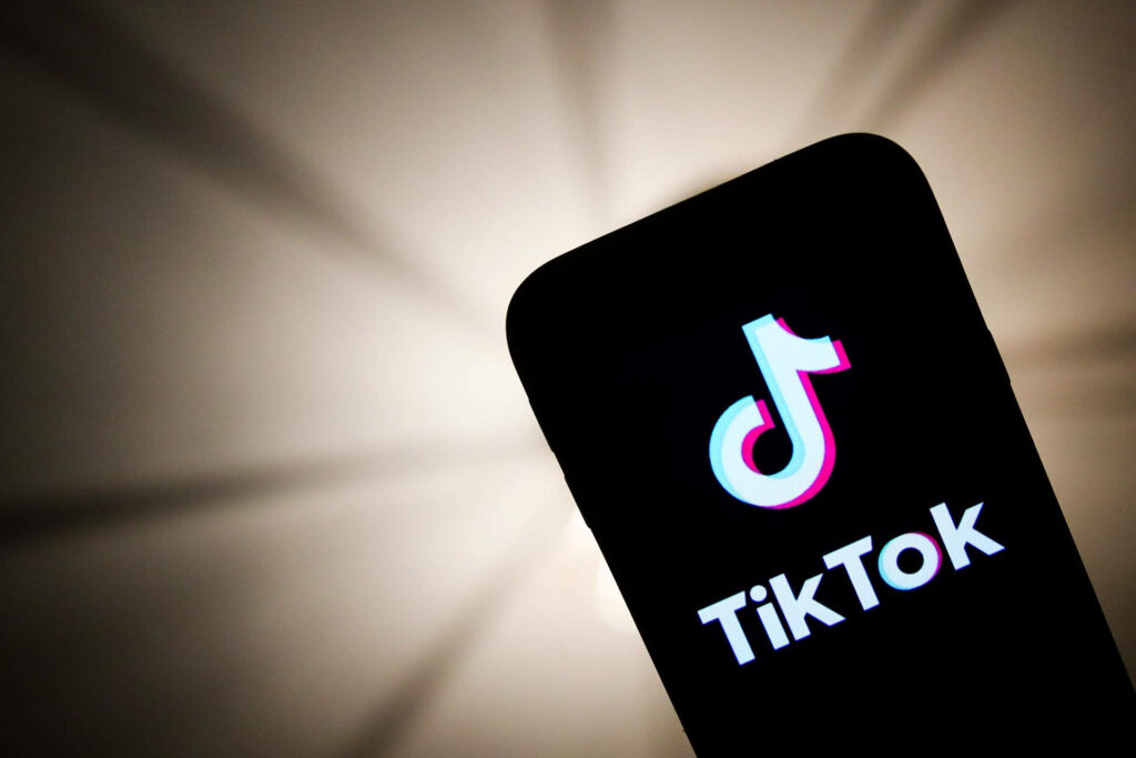 Smartphone showing vibrant TikTok logo on screen with soft lit modern wallpaper background