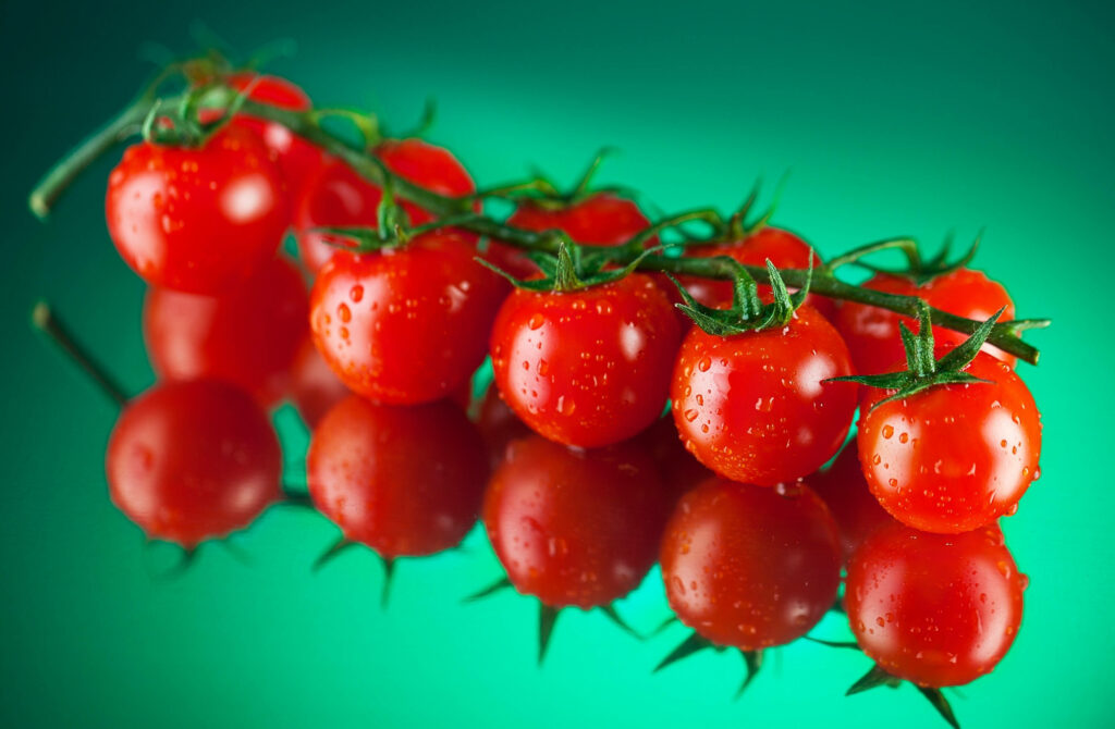 Vibrant Red Tomato Wallpaper with Glossy Reflection on Green Background