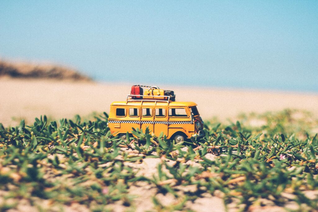 Playful Toy Bus Wallpaper: Adventure on Lush Grass & Sandy Background