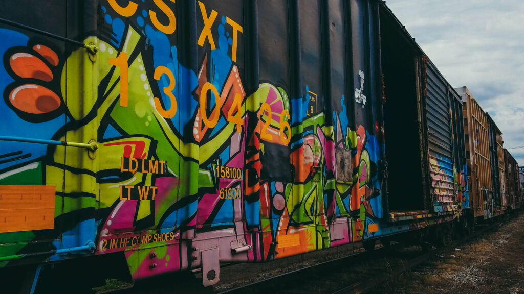 Graffiti Express: Vibrant Train Art Unleashed in Splashes of Spray Paint Wallpaper