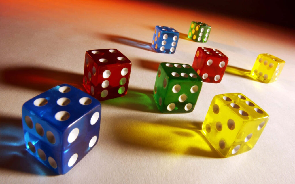 Colorful translucent dice in blue red yellow and green casting vivid shadows on soft surface Wallpaper