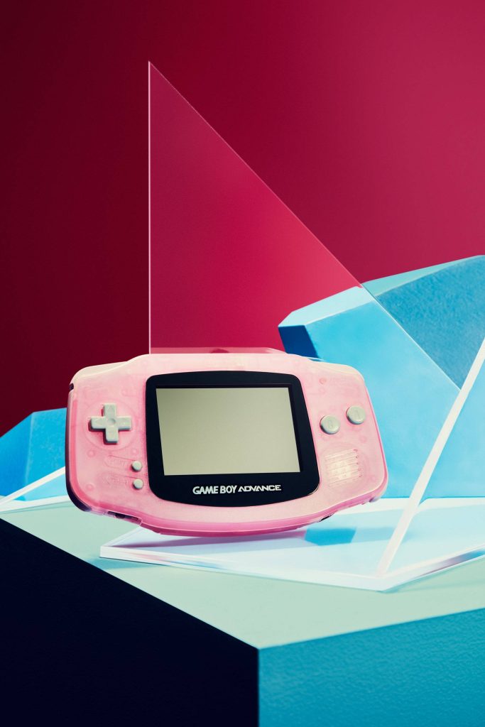 Translucent pink Game Boy Advance on blue platforms with bright magenta background wallpaper