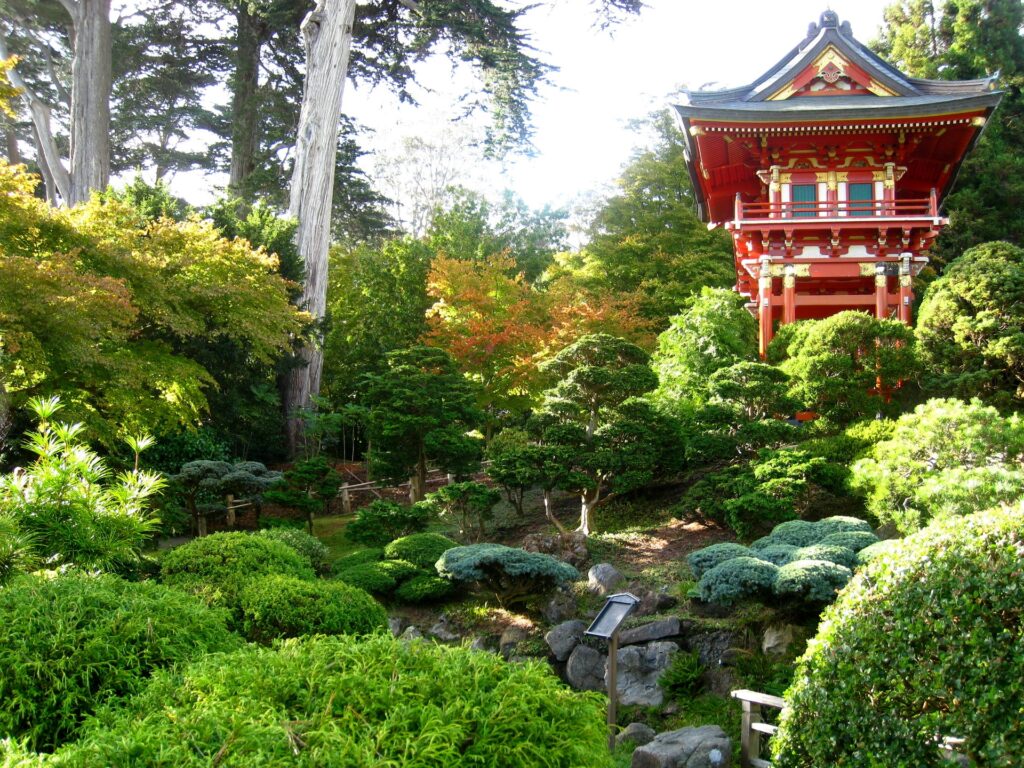 Vibrant tree nursery with lush greenery and traditional red gold Chinese arbor in sunlight background Wallpaper