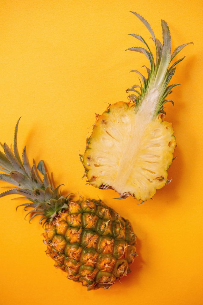 Vibrant pineapple wallpaper with whole fruit and juicy slice on sunny yellow tropical background