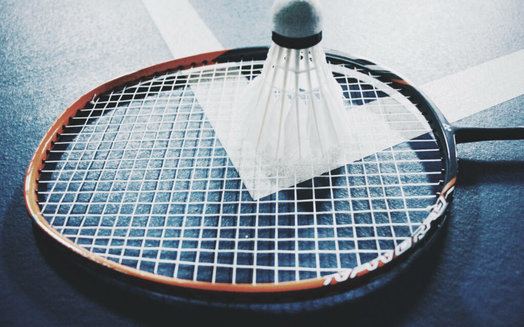 The Vibrant Fusion: A Captivating Orange Badminton Racket with an Upside Down Shuttlecock Wallpaper