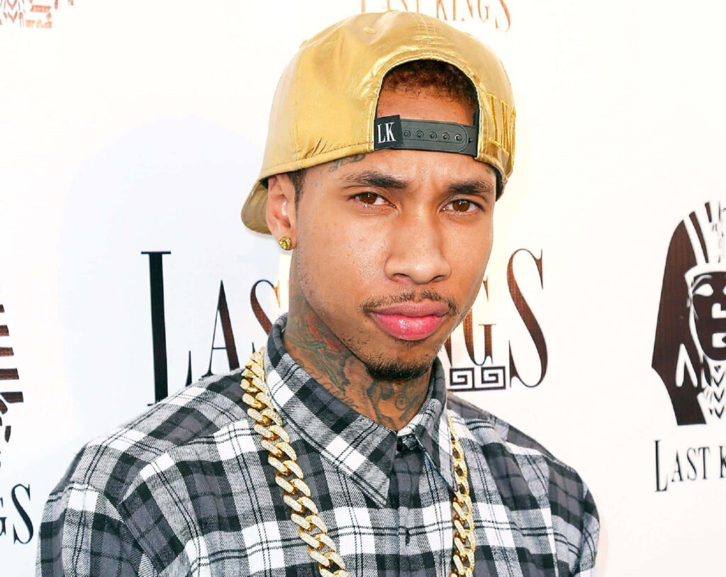 Tyga's Vibrant Wallpaper: Charismatic Style in Gold Cap & Chain