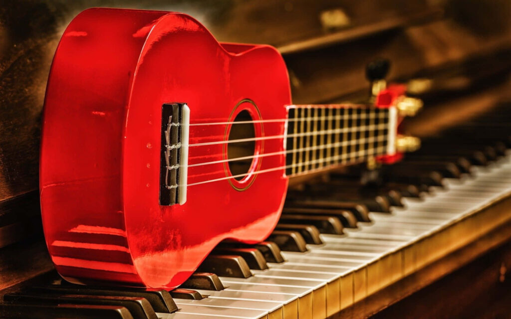 Vibrant Ukulele Wallpaper: Red Ukulele on Piano Keys Aesthetic