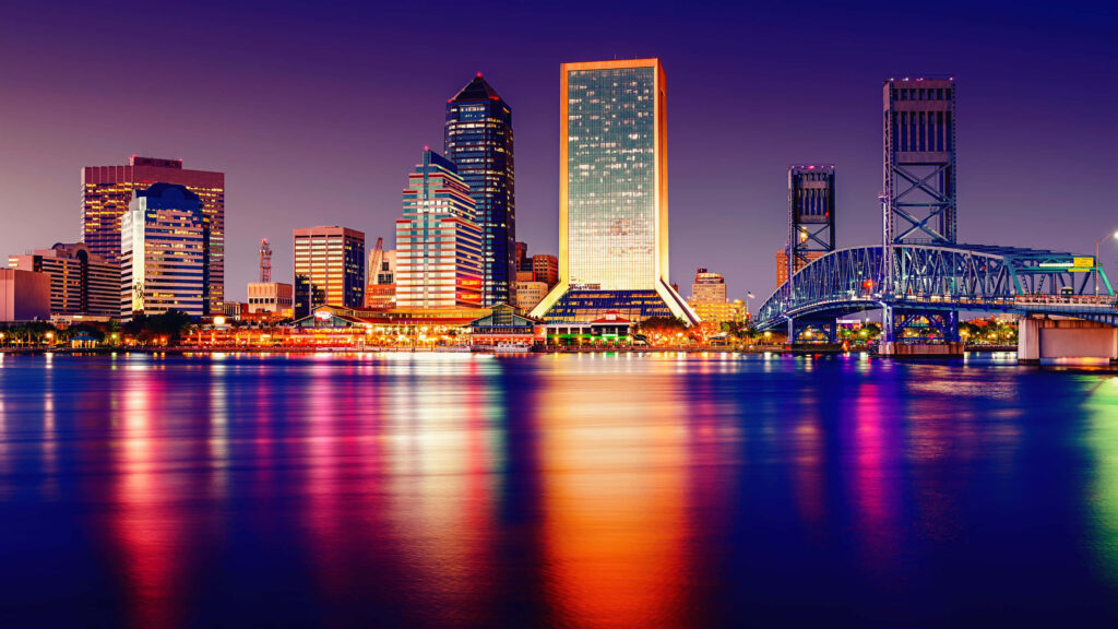 Vibrant Night Cityscape Wallpaper: Illuminated Skyscrapers & River Reflections