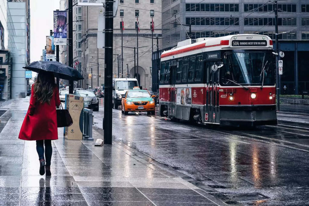 Vibrant Urban Rainy Scene: Woman in Red Coat on City Road Wallpaper